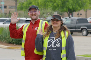 smiling CC’s Team Members waving in parking lot wearing safety vests